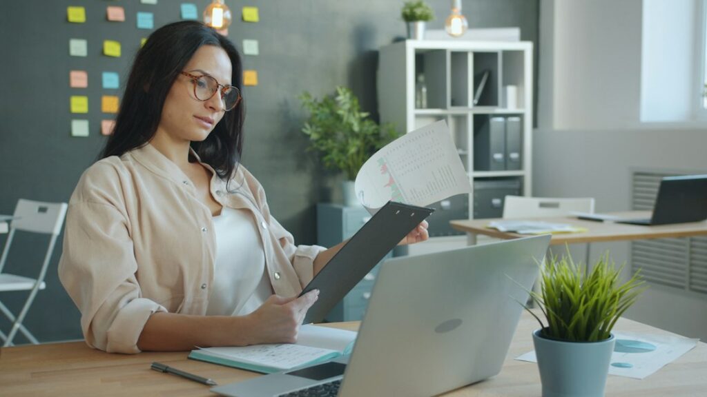 Business owner reviewing tax documents and a laptop to check which 1099 forms her S corp should receive